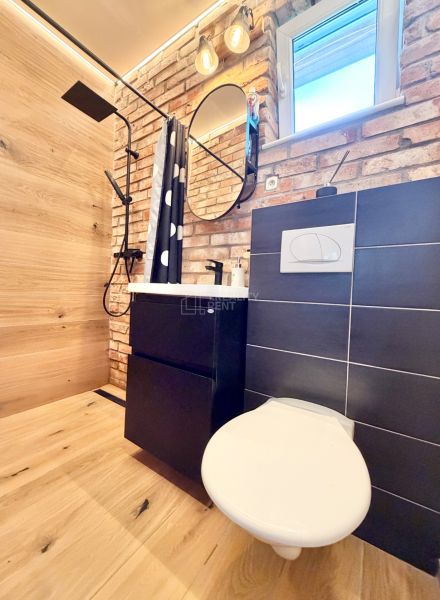 A bathroom with a shower, brick tiles, and a wooden decor floor in a family house.