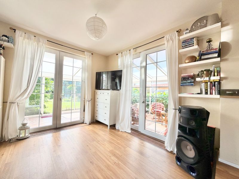Living room in a family house with white curtains, shelves, and a floor with a wood decor.