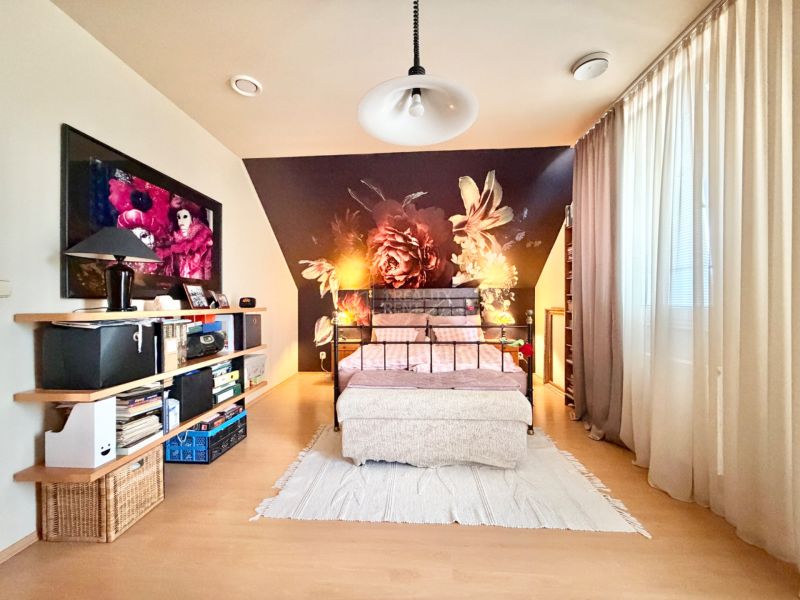 A bedroom in a family house with pink walls and a wooden decor floor.