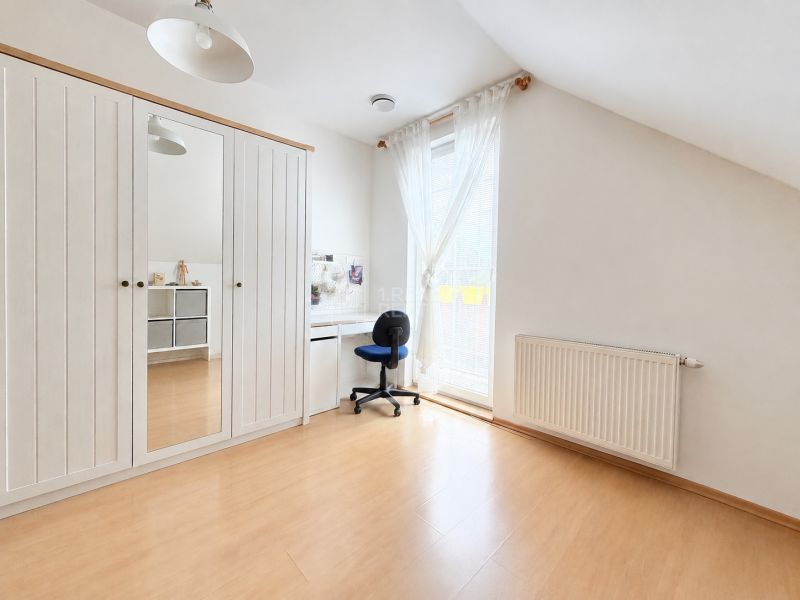 A brightly lit room in a family house with a wooden decor floor, a wardrobe, and a desk.