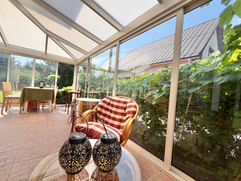 A glazed terrace with comfortable armchairs and a table in a family house.