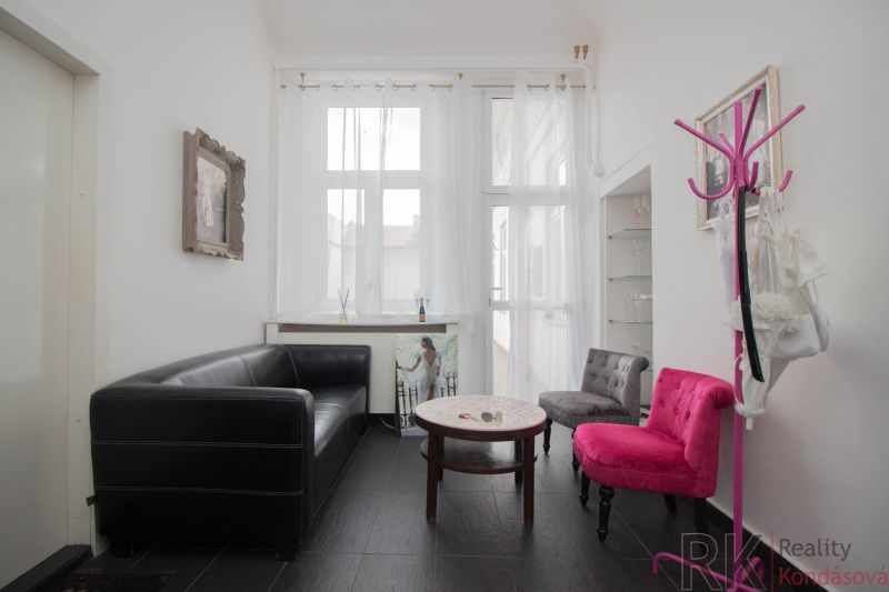 Commercial space with a black sofa, colorful chairs and a table, bright atmosphere.