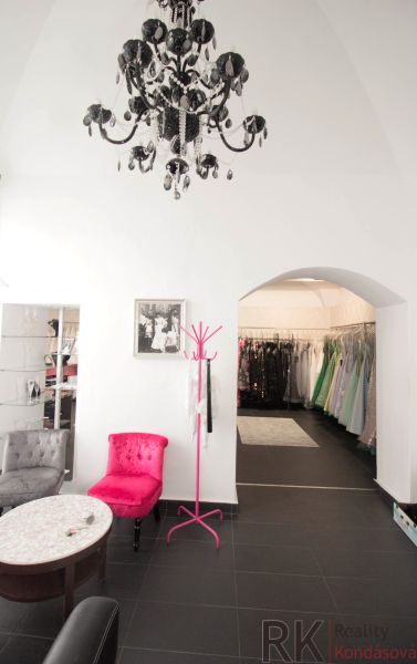 Black chandelier, pink armchair, coat rack, and dresses in commercial premises.