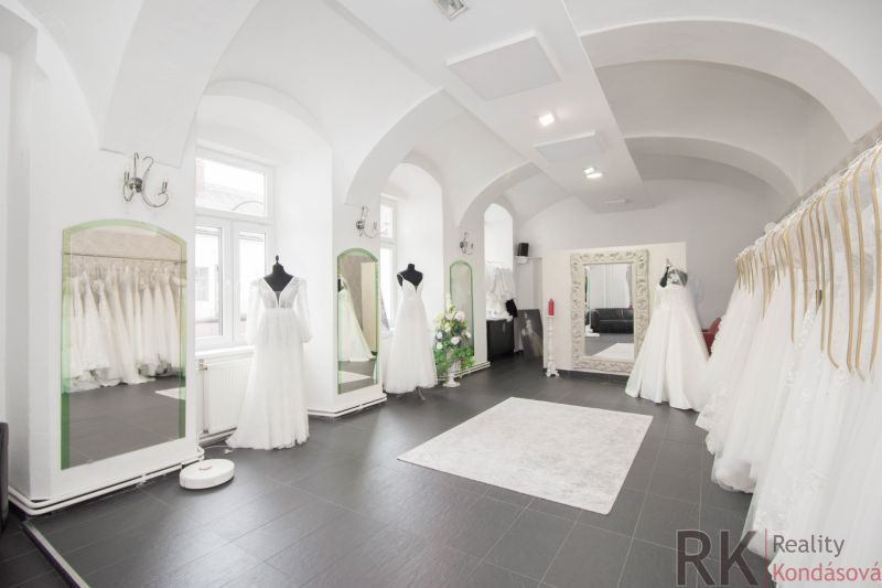 Commercial space with luxury wedding dresses and large mirrors, elegant lighting fixtures.