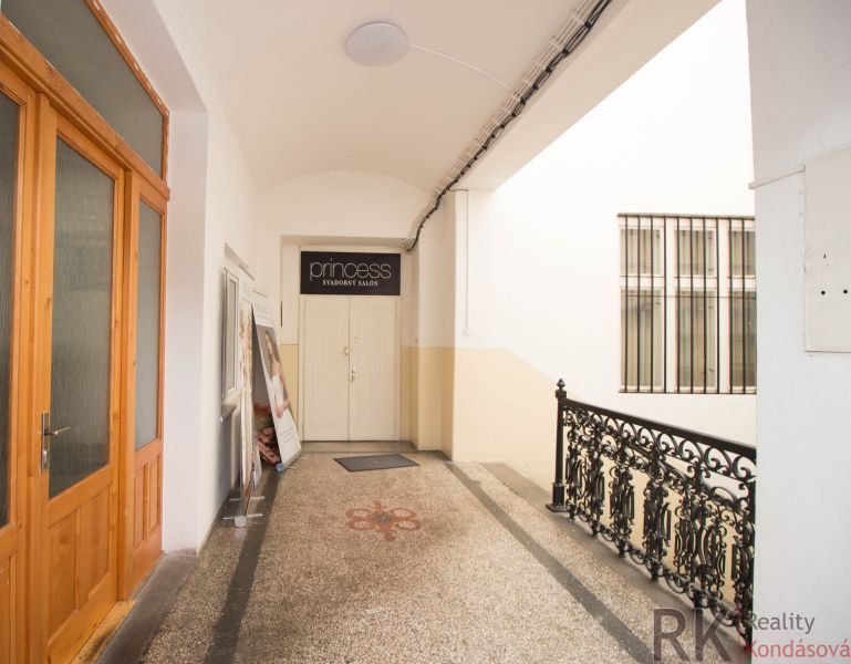 A corridor with commercial spaces with metal railings and white walls.