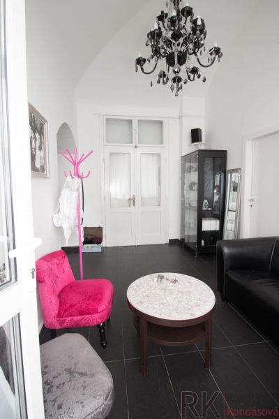 Commercial space with a black chandelier, colorful chairs, and a glass display case.