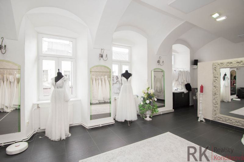 Commercial space with elegant wedding dresses, mirrors, and a black floor with decor.