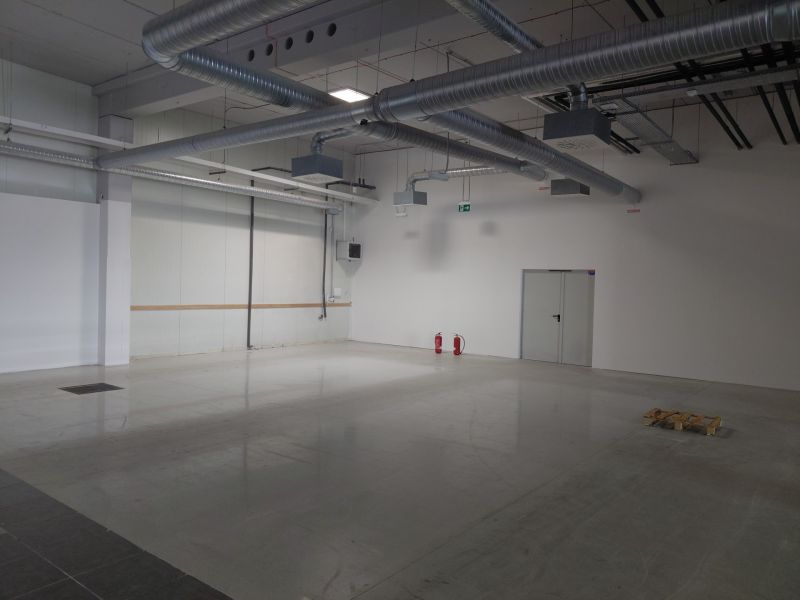 Empty industrial interior with concrete flooring and ventilation, commercial space.