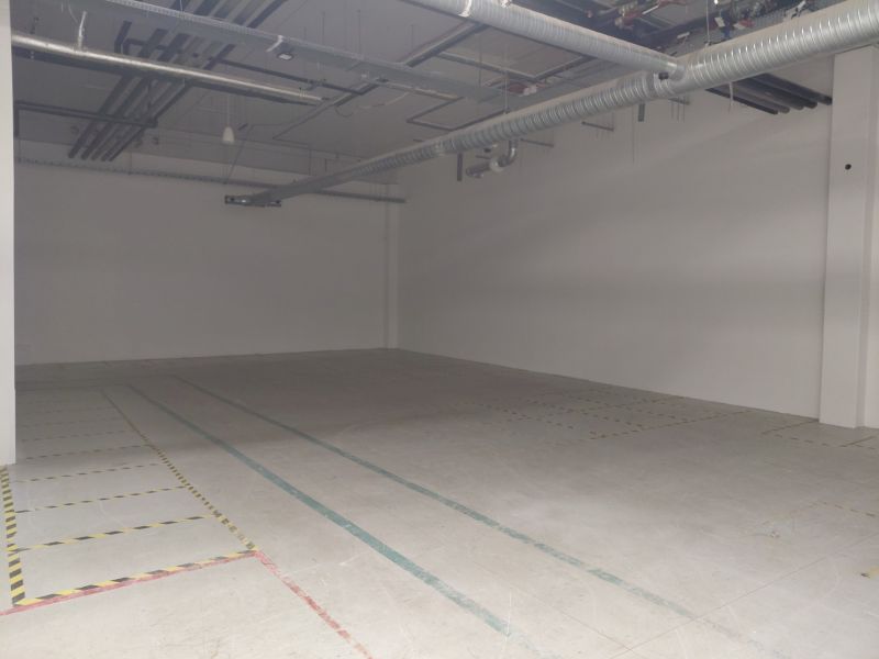 Empty commercial spaces with ceiling pipes and concrete floor.