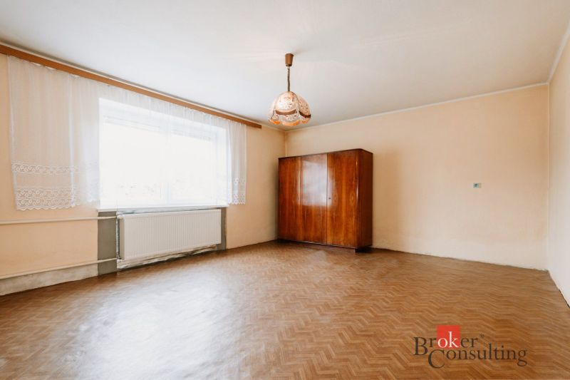 An empty room with a wooden floor, an antique wardrobe, and a curtain in a family house.