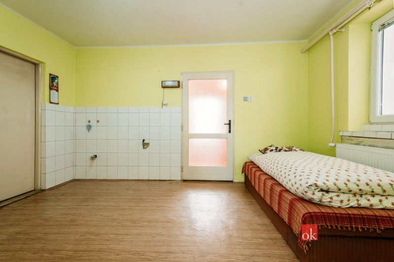 A room in a family house with a bed, tiles, and a wooden decor floor.