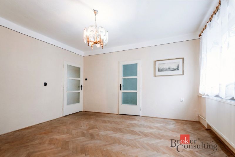A room in a family house with a wooden decor floor and a vintage chandelier.