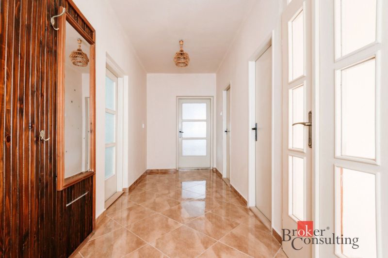 A hallway in a family house with tiles and a mirror on a wooden wall.