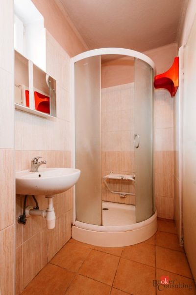 Bathroom in a family house with a shower and a sink, floor with wooden decor.