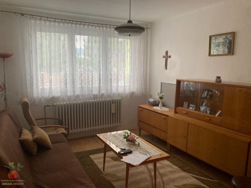 Living room in a 3-room apartment with a sofa, display cabinet, and wooden decor flooring.