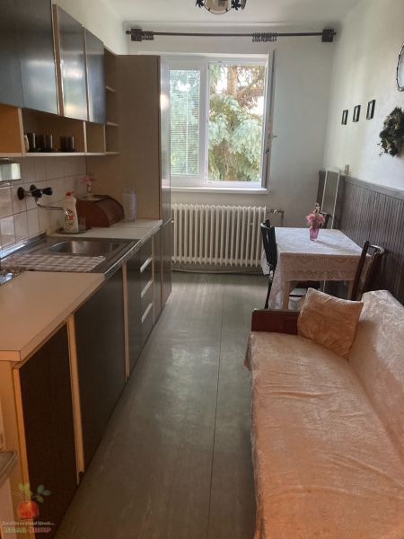 A kitchen in a 3-room apartment with a wooden decor floor and a sofa.