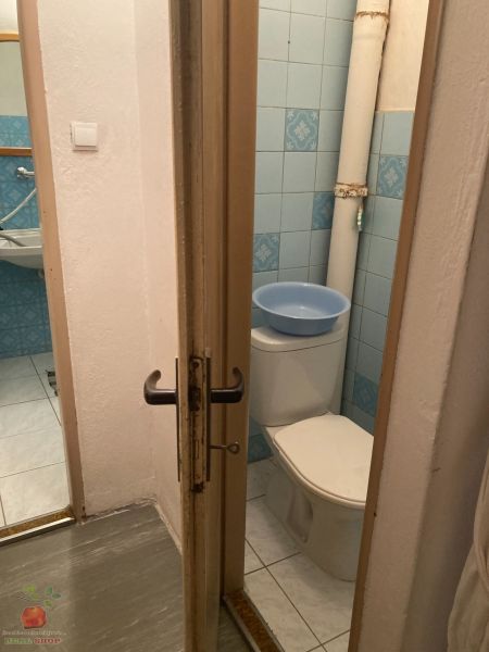 A toilet with light tiles and blue tiles in a 3-room apartment.