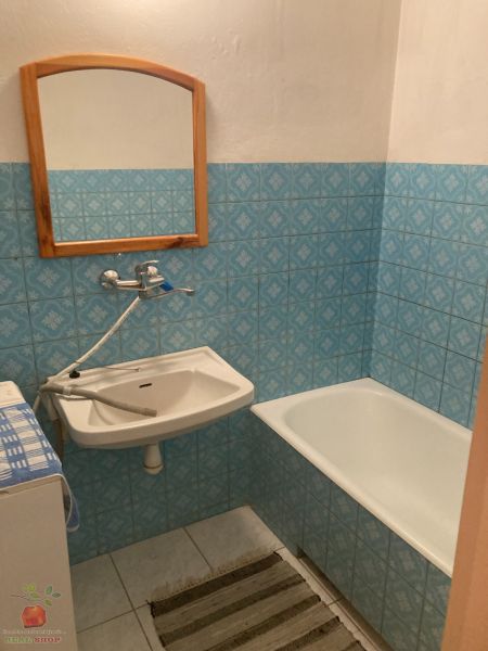 The bathroom in the three-room apartment has blue tiles, a bathtub, and a sink.
