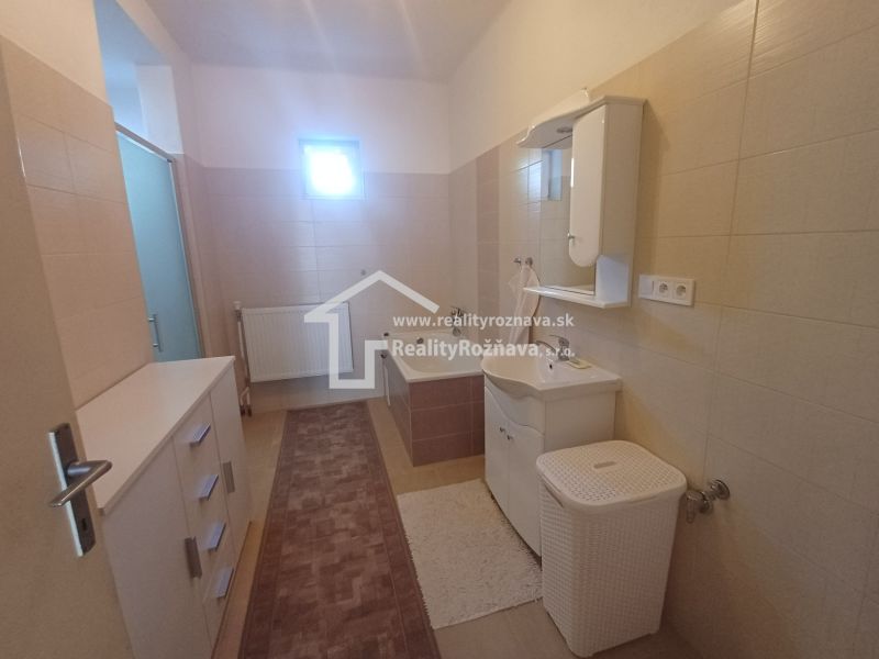 Bathroom in a family house with a bathtub, sink, and wooden decor tiles.