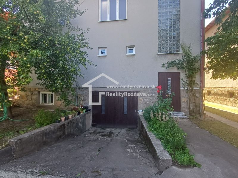 A family house in Rožňava with a garage and a garden surrounded by greenery.