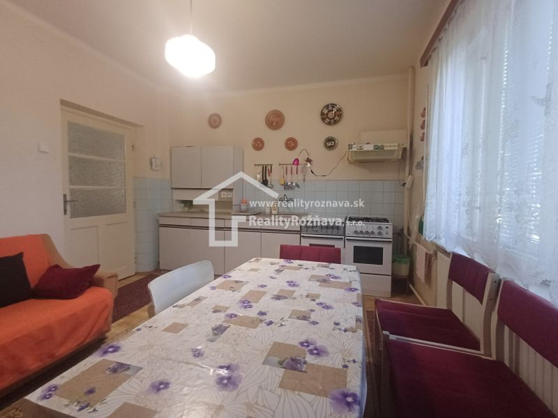 A kitchen in a family house with decorative plates on the wall, a dining table, and a couch.