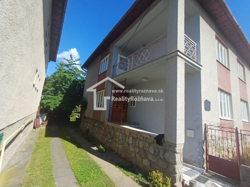A family house in Rožňava with a terrace and a stone wall, surrounded by greenery.