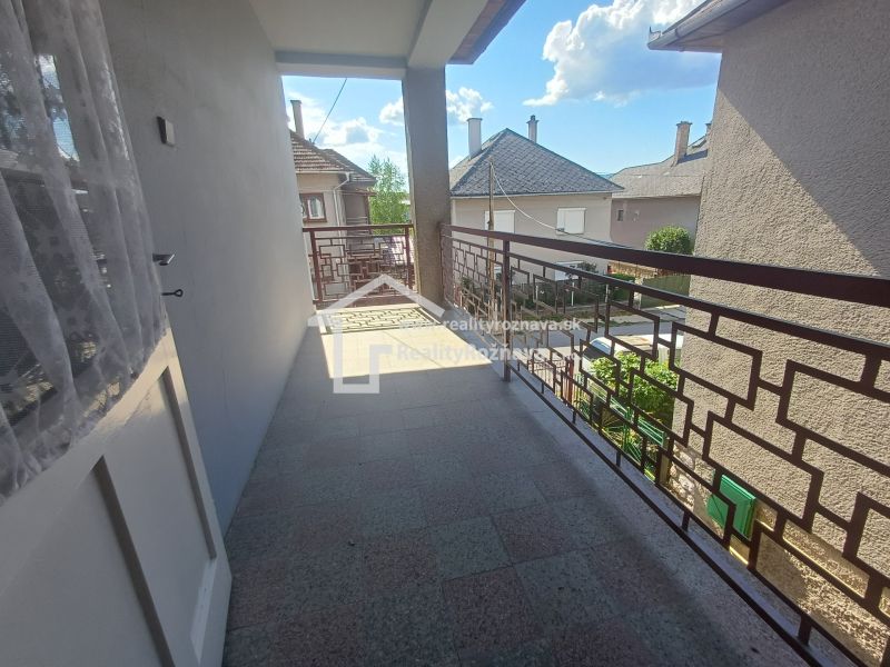 A balcony of a family house in Rožňava with a view of other houses and the sky.