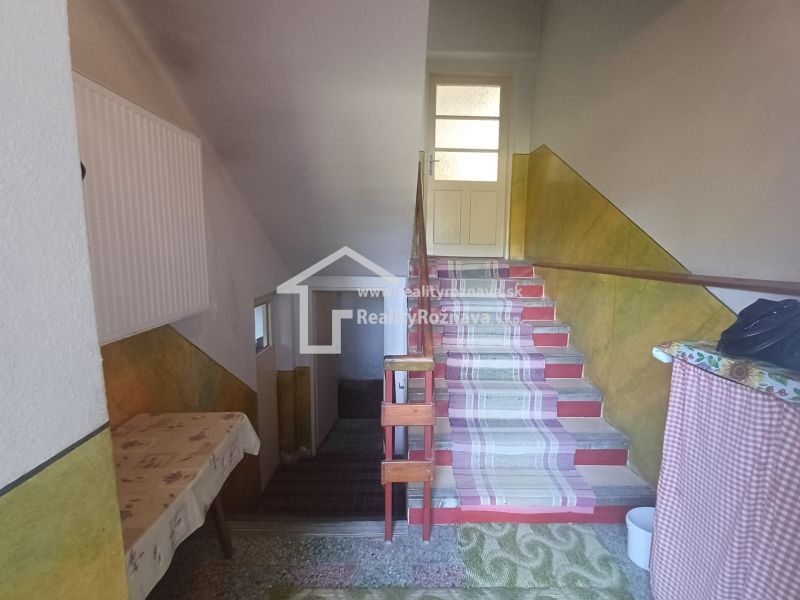 Interior of a family house with a staircase, carpets, and a table.