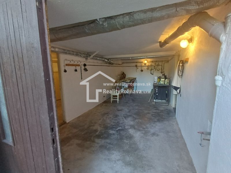 Basement of a family house with industrial pipes, lighting, and a work table.