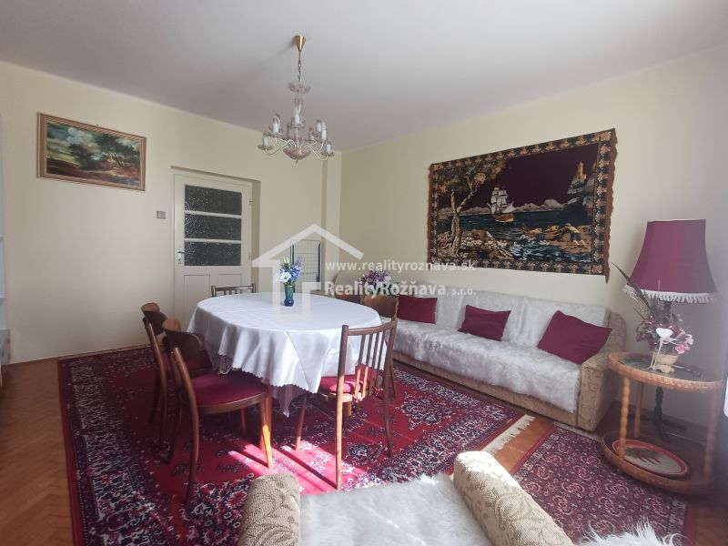 Living room with a red carpet, round table, and sofa in a family house.