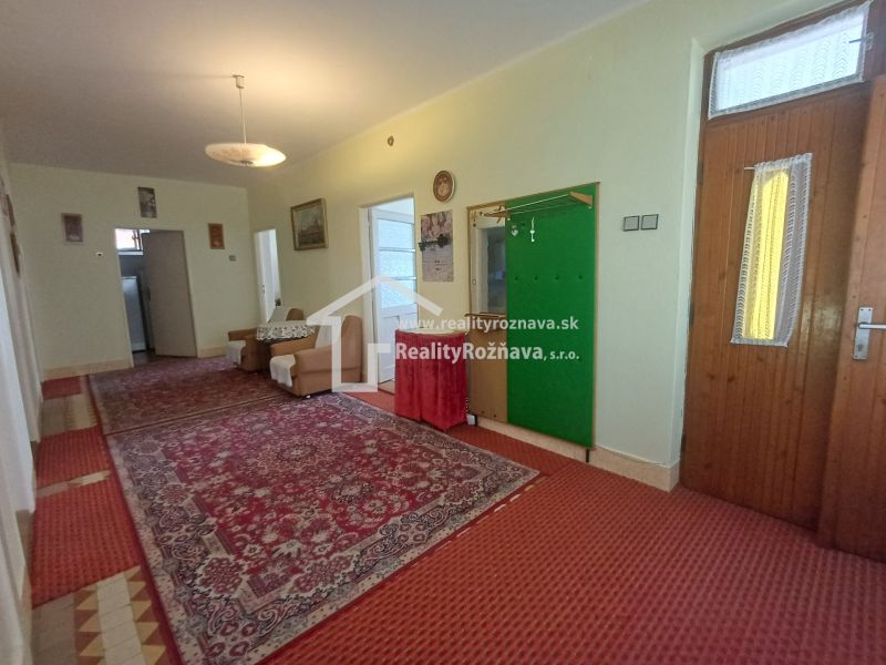 A hallway in a family house with a carpet, comfortable sofas, and a built-in coat rack.