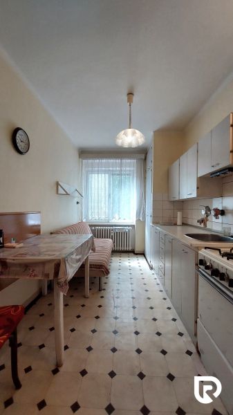 A kitchen in a 2-room apartment with a dining table, light, and a tiled pattern floor.