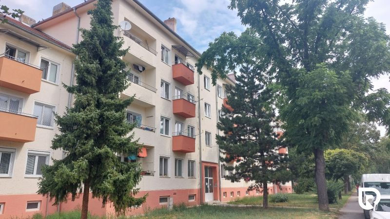 Apartment building with balconies surrounded by greenery on 28th October Street in Trenčín.