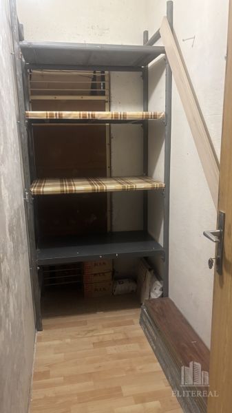 A storage room with shelves and a floor with a wooden decor in a 3-room apartment.