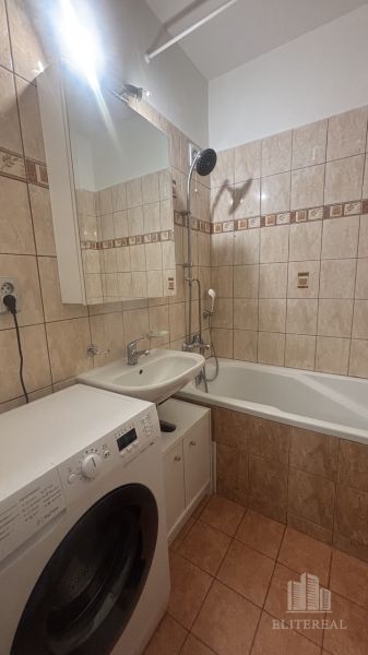 Bathroom in a 3-room apartment with a bathtub, washing machine, and tiled walls.
