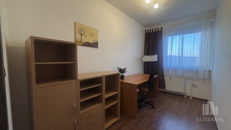 A study with a desk, chair, and shelves in a 3-room apartment with a wooden decor floor.