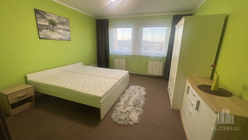 A bright bedroom with a double bed, green walls, and a wardrobe in a 3-room apartment.