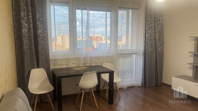 Dining area with a table, white chairs, and a floor with a wooden decor in a 3-room apartment.