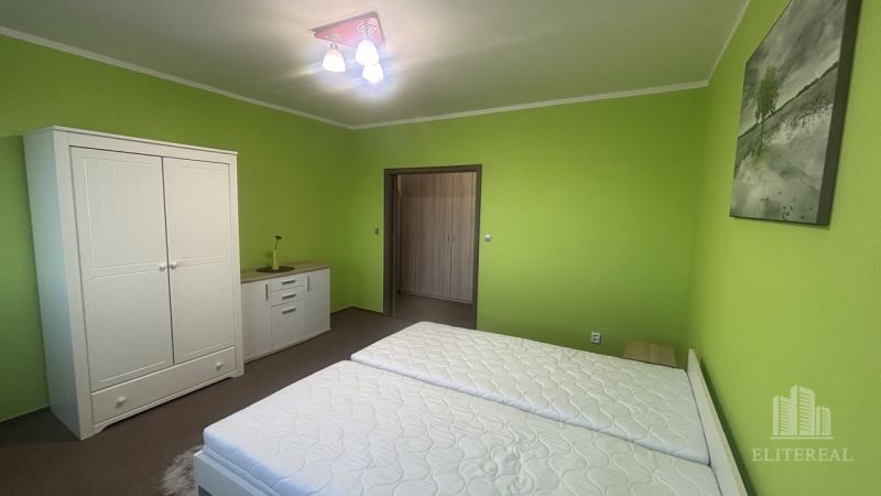 A bedroom in a 3-room apartment with light furniture and green walls.