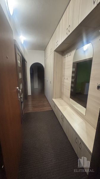 A hallway in a 3-room apartment with storage space and a mirror, with a floor featuring a wooden decor.