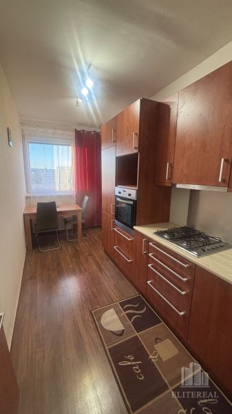 A kitchen in a 3-room apartment with a wooden decor floor and a dining table.