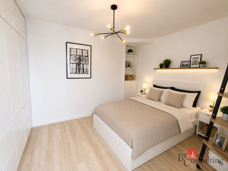 A bright bedroom with a bed, decor, a hanging lamp, and a wood-patterned floor in a studio apartment.