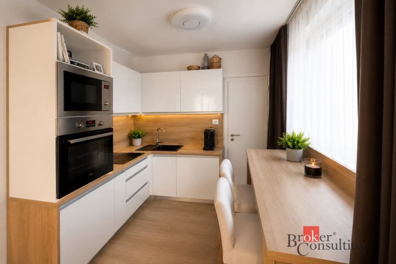 A kitchen in a studio apartment with white cabinets and a wood-patterned floor.