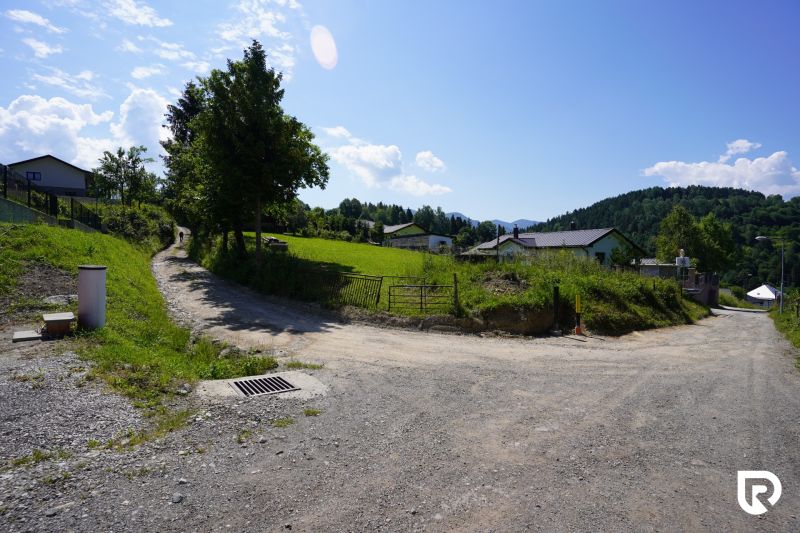 Recreational plots in Lysice with a dirt road and green meadows under a blue sky.