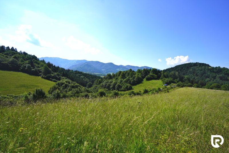 A landscape in Lysice with recreational plots, surrounded by meadows and wooded hills.