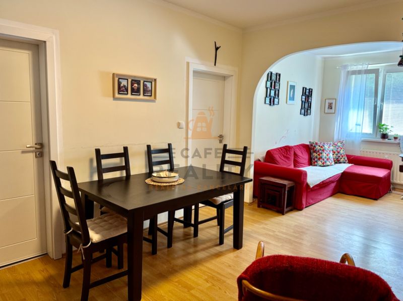 Dining area with a red sofa and wooden floor decor in a three-room apartment.