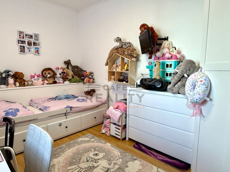 Children's room with a bed, plush toys, and a floor with a wooden decor in a 3-room apartment.