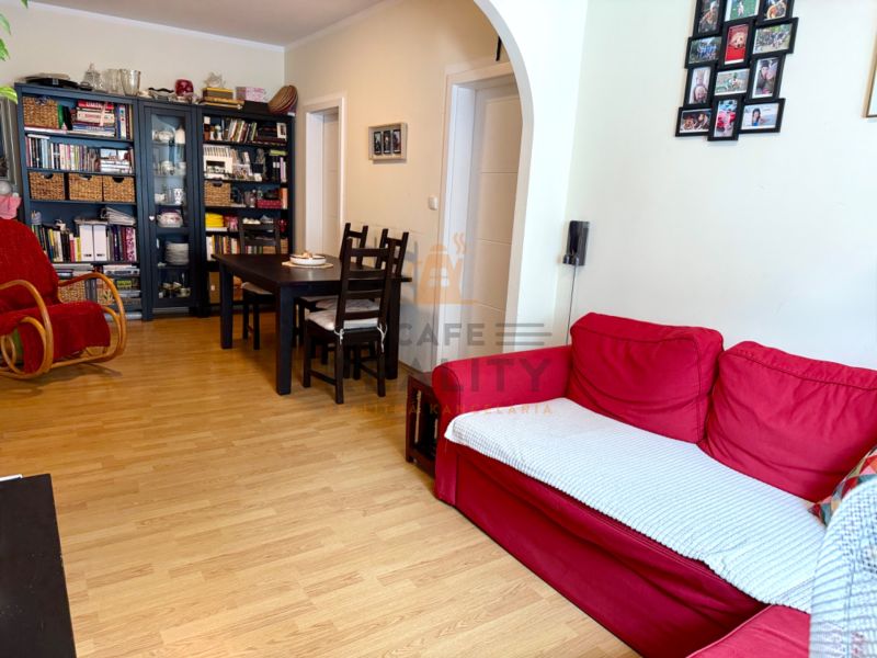 Living room with a red sofa, shelves, a rocking chair, and a wooden-patterned floor.