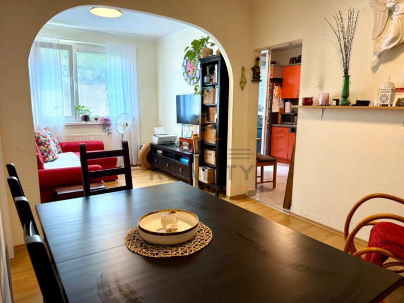 Interior of a 3-room apartment with a living room, kitchen, wooden decor flooring, and a dining table.