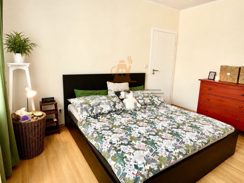 A bedroom in a 3-room apartment with a bed, green details, and a floor with a wooden decor.